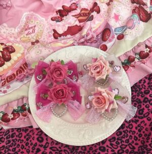 Hime Gyaru rose hair clip with heart faux pearls and rhinestones flat lay display on decorative white plate with pink dessert cloth and leopard print background