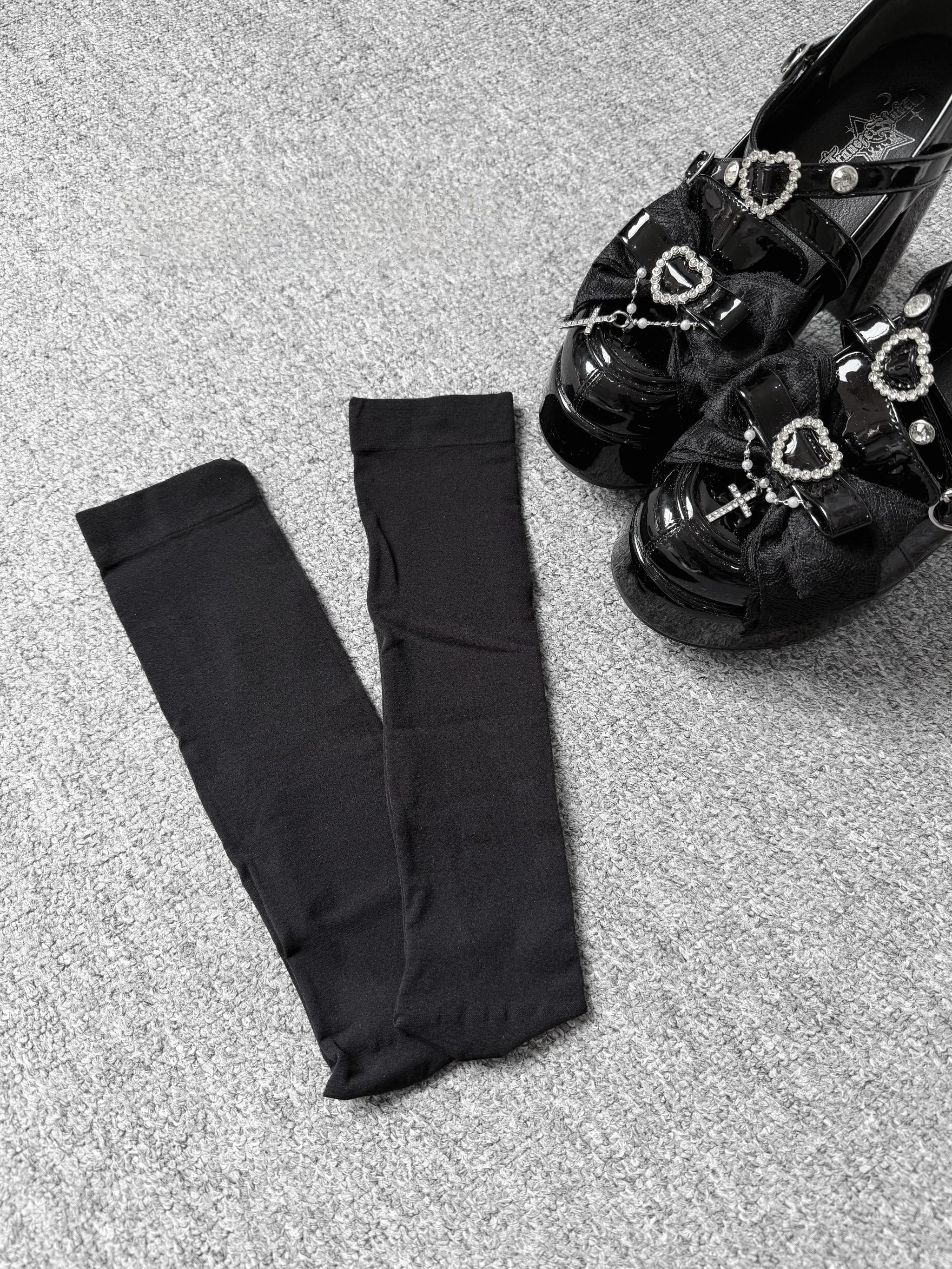 Black knee-high calf socks flat lay arrangement with black bow platform loafers sheer fabric detail