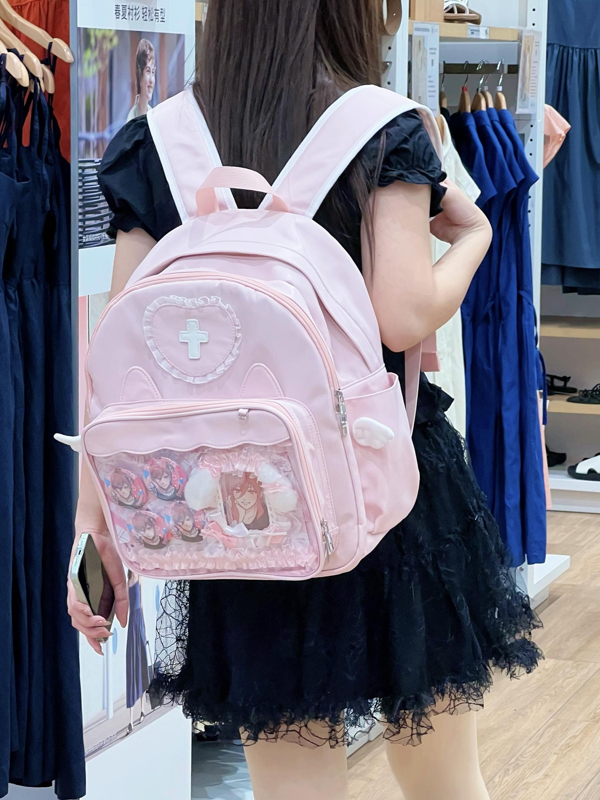 Pink aesthetic Jirai Kei itabag backpack featuring transparent display window, celestial heart embellishments and angel wing side decorations for kawaii fashion collectors