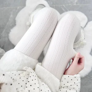 Cable knit textured footed tights in pure white displayed on legs wearing polka dot pajama set, top-down view showing twisted cable knit woven texture detail, ideal for layered Jirai Kei styling