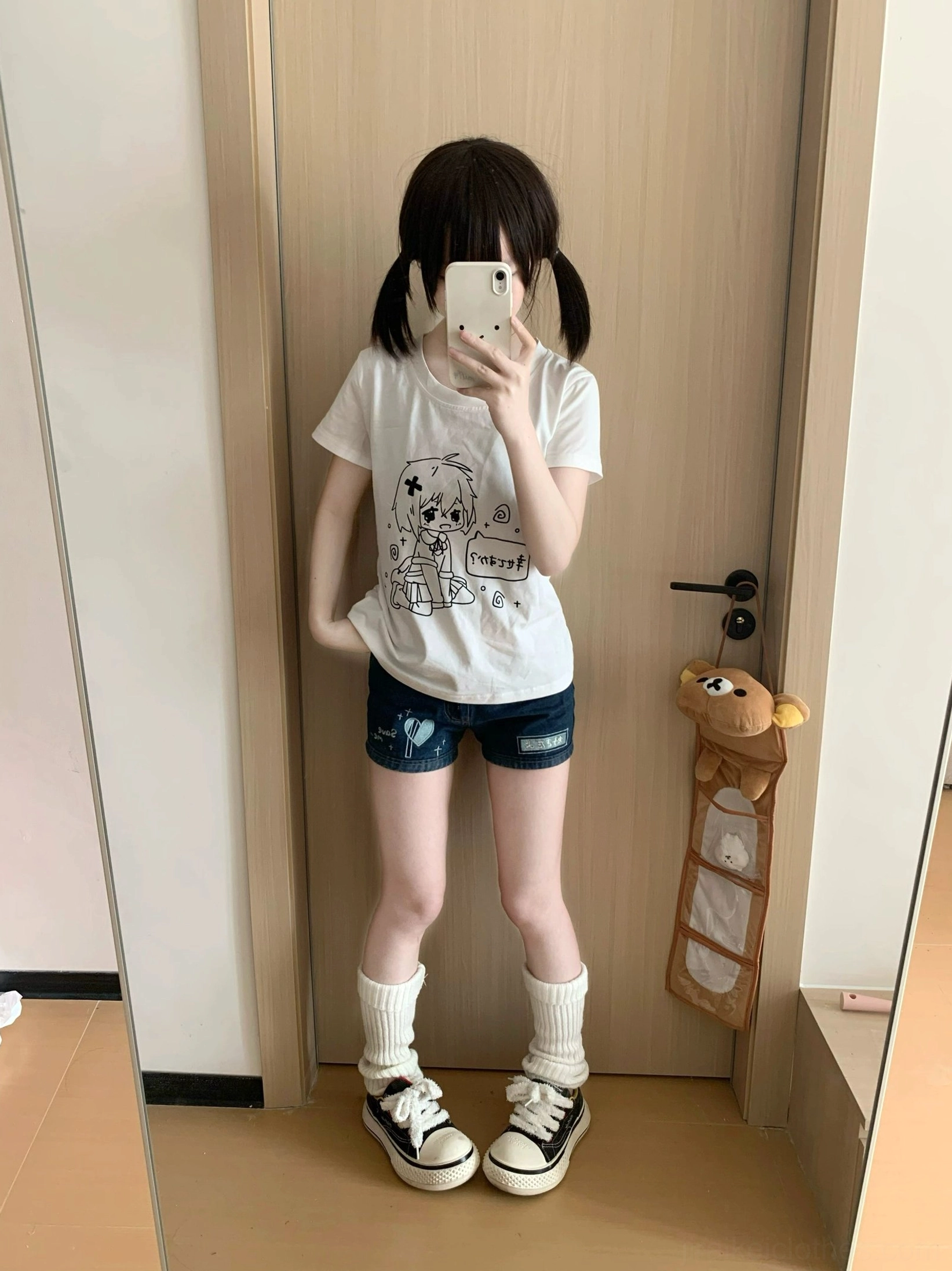 Casual anime graphic white tee on model with hand in pocket relaxed pose full-length mirror doorway view