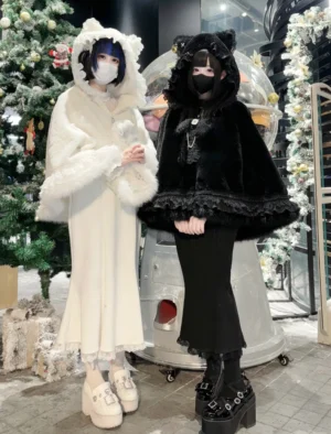 Close-up front view of black and white cat ear hooded fleece cape coats showing sleeve design, lace hem trim, and plush fabric texture details