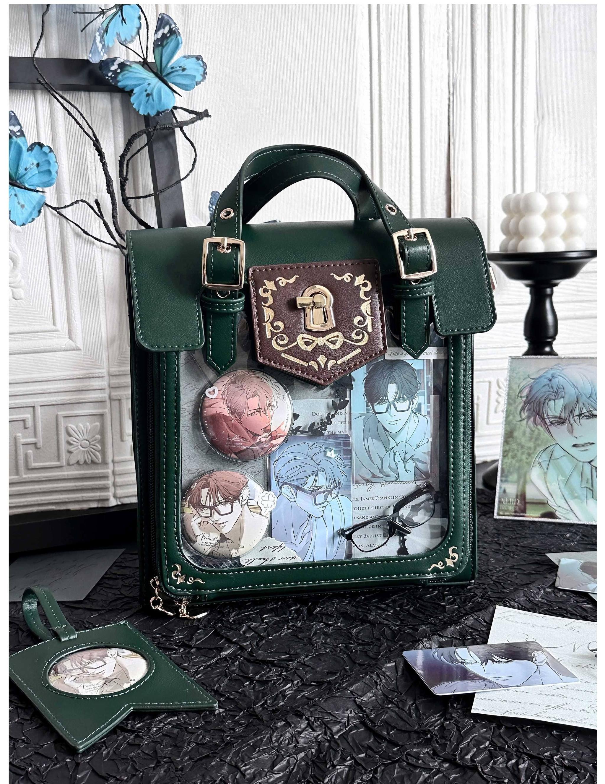 Dark green vintage Jirai Kei ita satchel bag with black trim and gold hardware featuring clear display window filled with colorful anime badges, three-quarter side view on vintage tabletop
