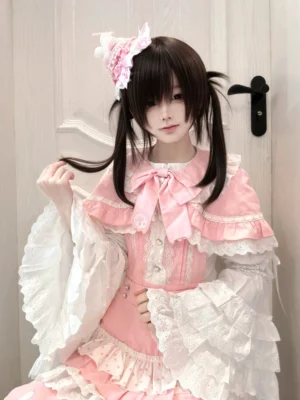 Pink lolita salopette dress with matching cape and short sleeve shirt, complete jirai kei outfit set with layered ruffles and decorative bow, three-quarter front view showing capelet and detailed lace sleeves