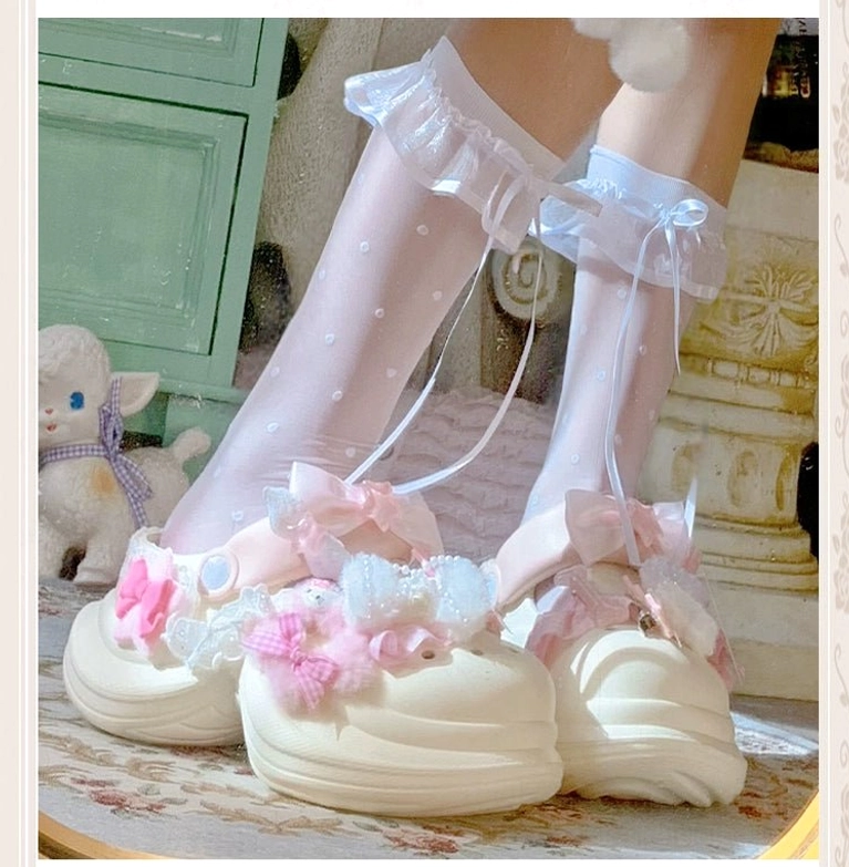 Cream-colored Jirai Kei kawaii clog sandal with pink flower embellishment, bow decoration, plush fuzzy fabric details, worn with ruffled bow-trim polka-dot socks
