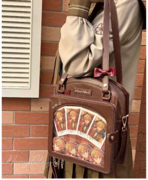 Brown anime ita crossbody bag with red bow accent and badge display window worn on model against brick wall background, perfect for Jirai Kei aesthetic lovers and anime collectors