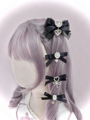 Black swallowtail bow hair clips with rhinestone and pearl heart pendant accents worn on lavender mannequin head left rear angle view Jirai Kei aesthetic