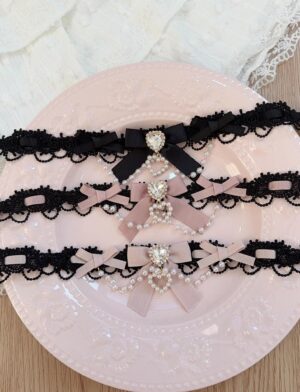 Jirai Kei lace chokers flatlay collection featuring three color variations with heart-shaped rhinestone pendants, scalloped lace trim, and ribboned bowknots displayed on pink ceramic plate