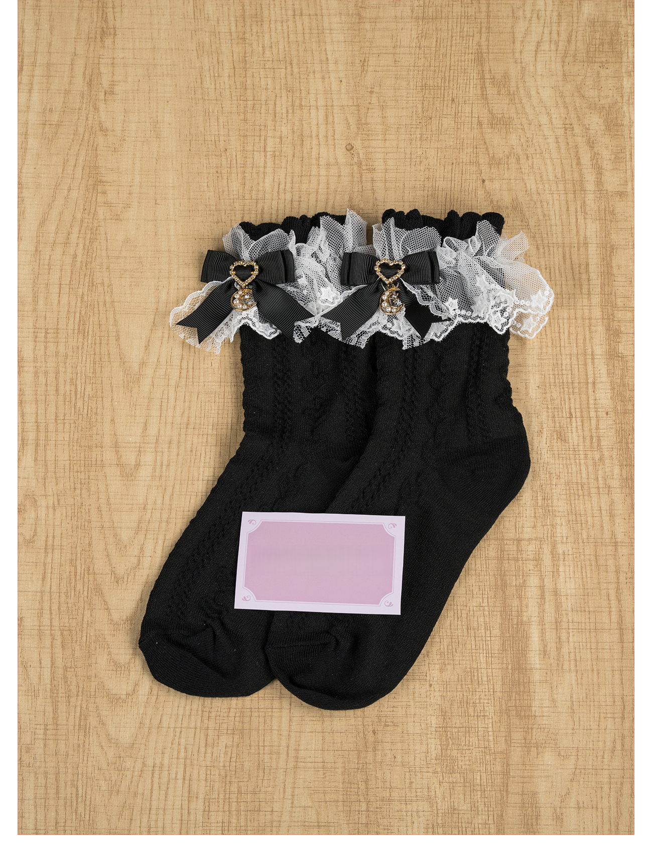 Black Jirai Kei ankle socks with black bow moon charm pendant, ruffled lace cuff, twisted knit fabric texture, flat lay view