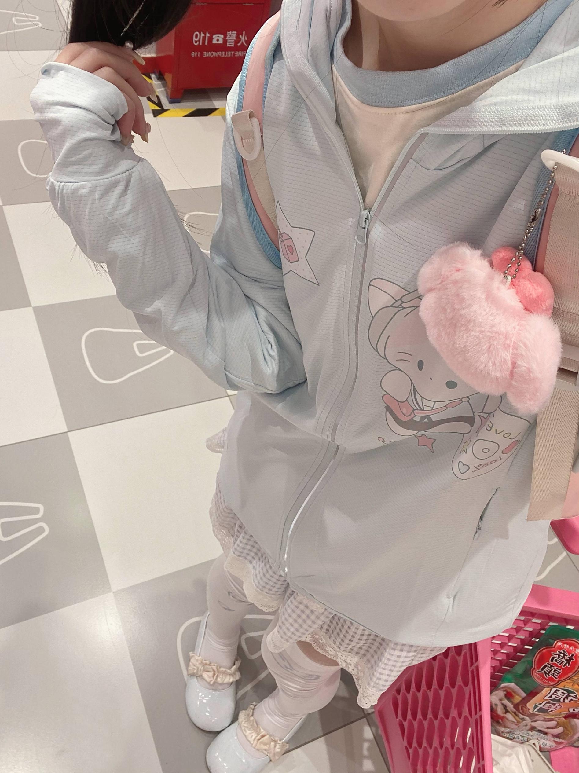 Side profile view of water blue jirai kei sun-protective jacket on model in checkered floor space, displaying printed motifs and hooded design