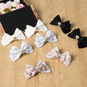 Jirai Kei four-layer bow hair clips collection flat lay display showing multiple color options black white gray-blue gray-pink with heart rhinestone center embellishments on wooden desk