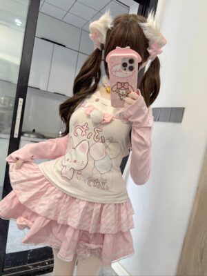 Kawaii cat-print two-piece coordinate with pom-pom bow chest decoration and layered ruffled skirt, side mirror perspective showing back silhouette and volume of tiered design with twin ponytail hairstyle