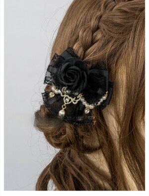 Close-up back view of black rose hair clip with lace bow base pearl trim and dangling pearl charm on braided hair