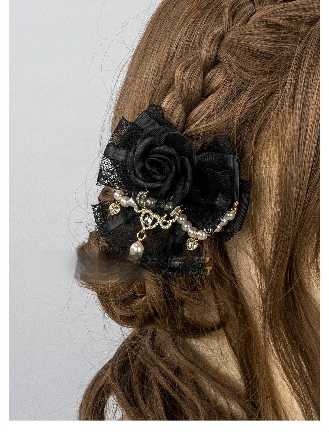 Close-up back view of black rose hair clip with lace bow base pearl trim and dangling pearl charm on braided hair