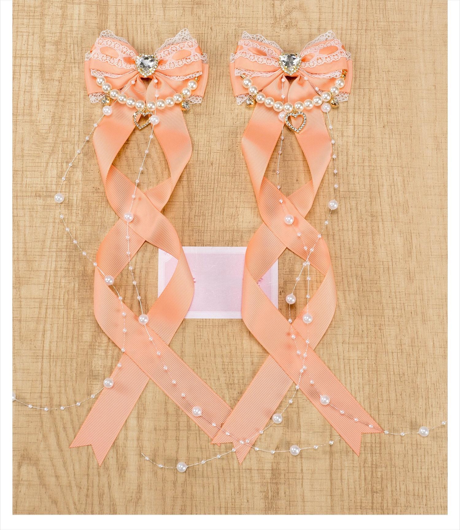 Jirai Kei light orange bow hair clips with ribbon knit fabric pearl chain trim and rhinestone heart displayed on neutral background