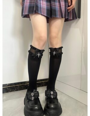 Black mid-calf Jirai Kei socks with scalloped ruffled cuffs and cross charm pendant styled with plaid pleated skirt and platform loafers front view