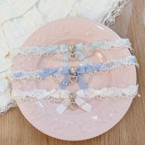Multiple Jirai Kei lace choker styles in light blue and white tones with bowknot designs, rhinestone decorations, and pearl chain accents arranged on vintage wooden table