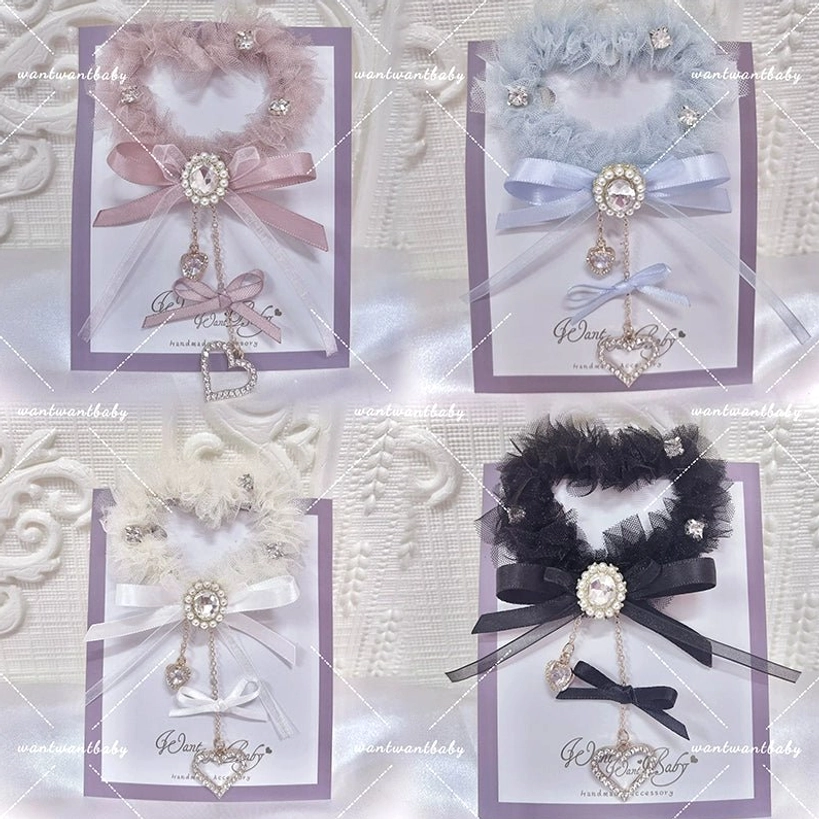 Top-down flat lay display of four color variants of heart-shaped tulle hair clips: pink, light blue, ivory, and black