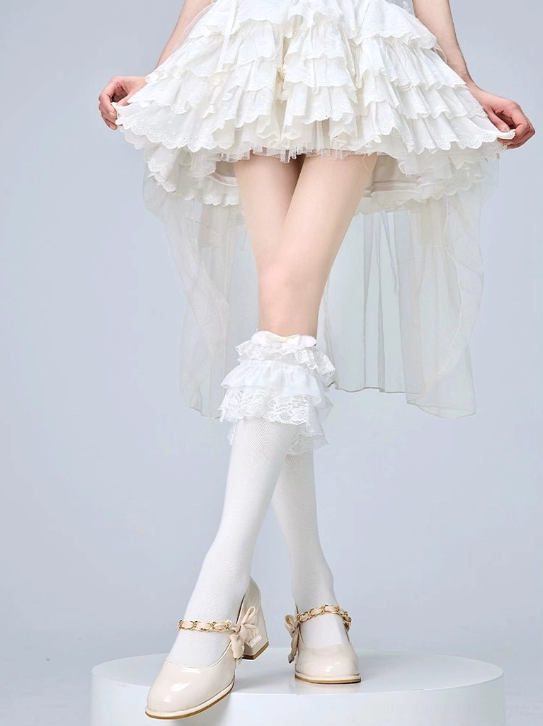 Frilled white jirai kei lolita calf socks with decorative lace cuff and bow details worn with white ruffled skirt and beige mary jane shoes