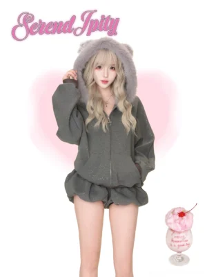 Front full-body shot of fuzzy bear ear jirai kei hoodie jacket and ruched shorts set in dark grey glitter, worn by model on pink backdrop