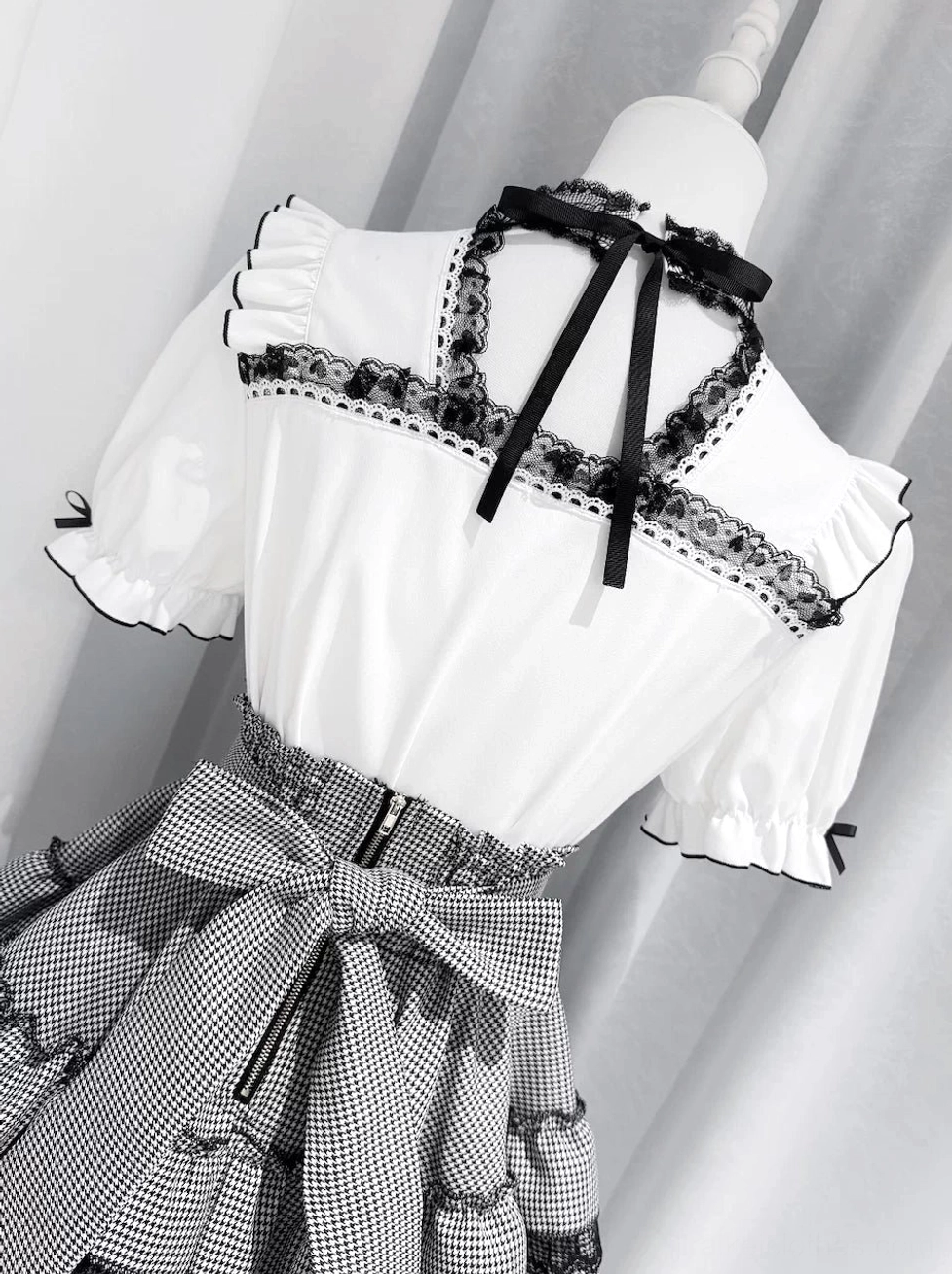 Model wearing black and white gingham Jirai Kei tiered skirt with corset front blouse bow hair accessory fashion shop