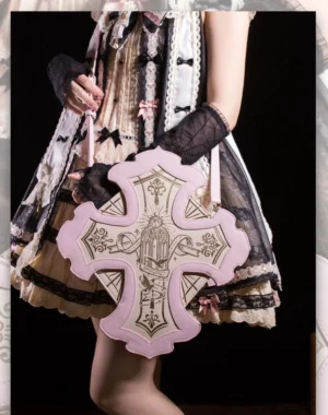 Gothic cross-shaped Jirai Kei lolita handbag in pink and off-white with religious gold embroidery details on model wearing sweet Gothic lolita dress with black gloves