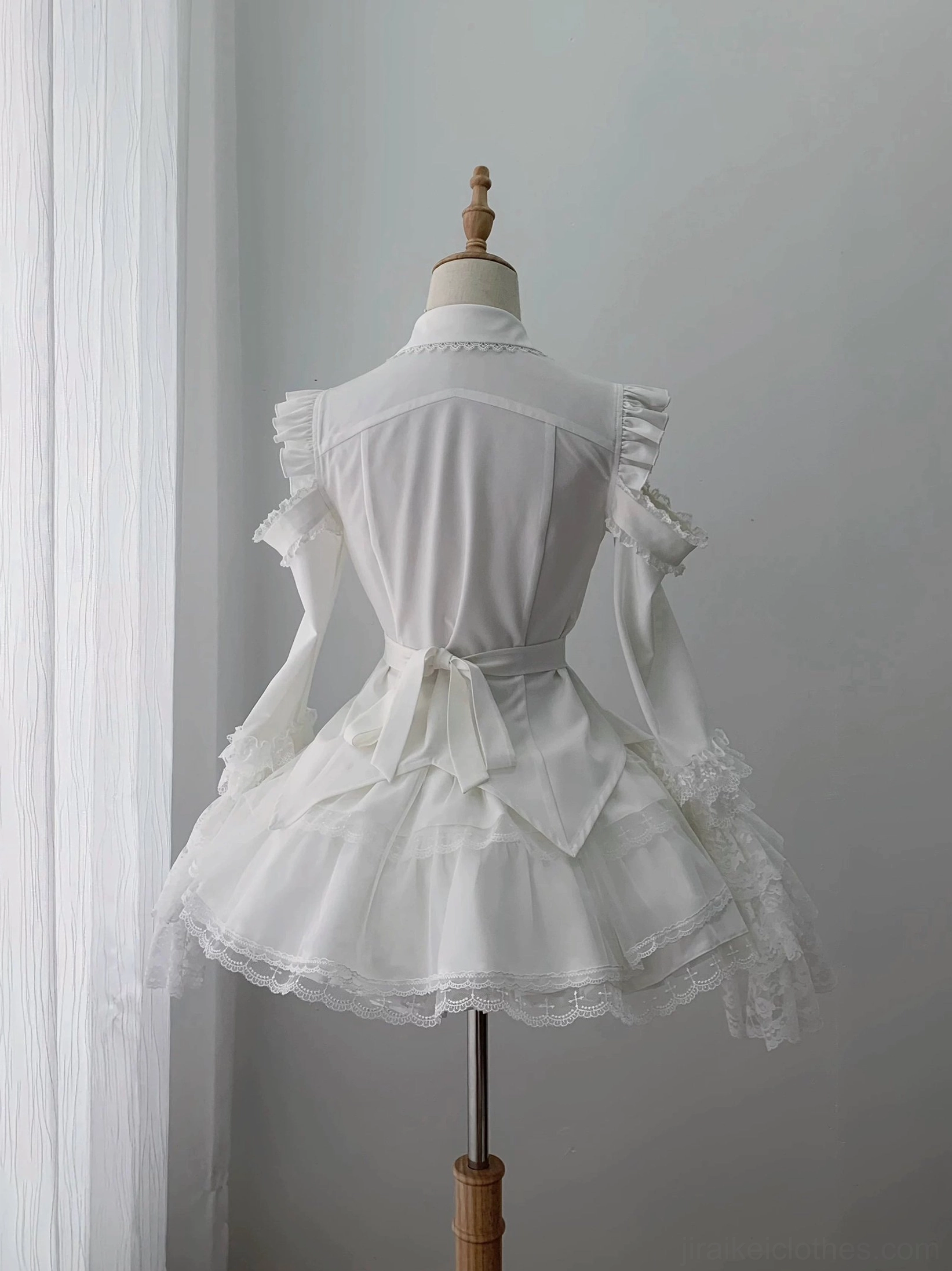 Back view of gothic lolita blouse and tiered skirt set on mannequin featuring waist sash belt and ruffled shoulder trim