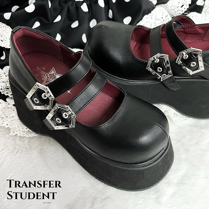 Solid black leather Mary Jane platform shoes with dual silver buckles thick platform sole and dark red insole front three-quarter view on polka dot fabric
