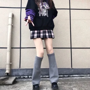 Gray flared over-knee leg warmers jirai kei style paired with plaid skirt and graphic sweatshirt street fashion look