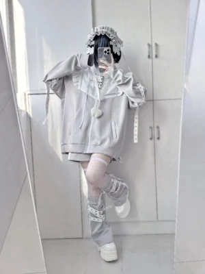 Gray Tenshi Kaiwai detachable wing jacket with ruffled collar and heart pendant, worn by gothic lolita model in mirror selfie, full-body front view showing coordinated leg warmers and platform boots