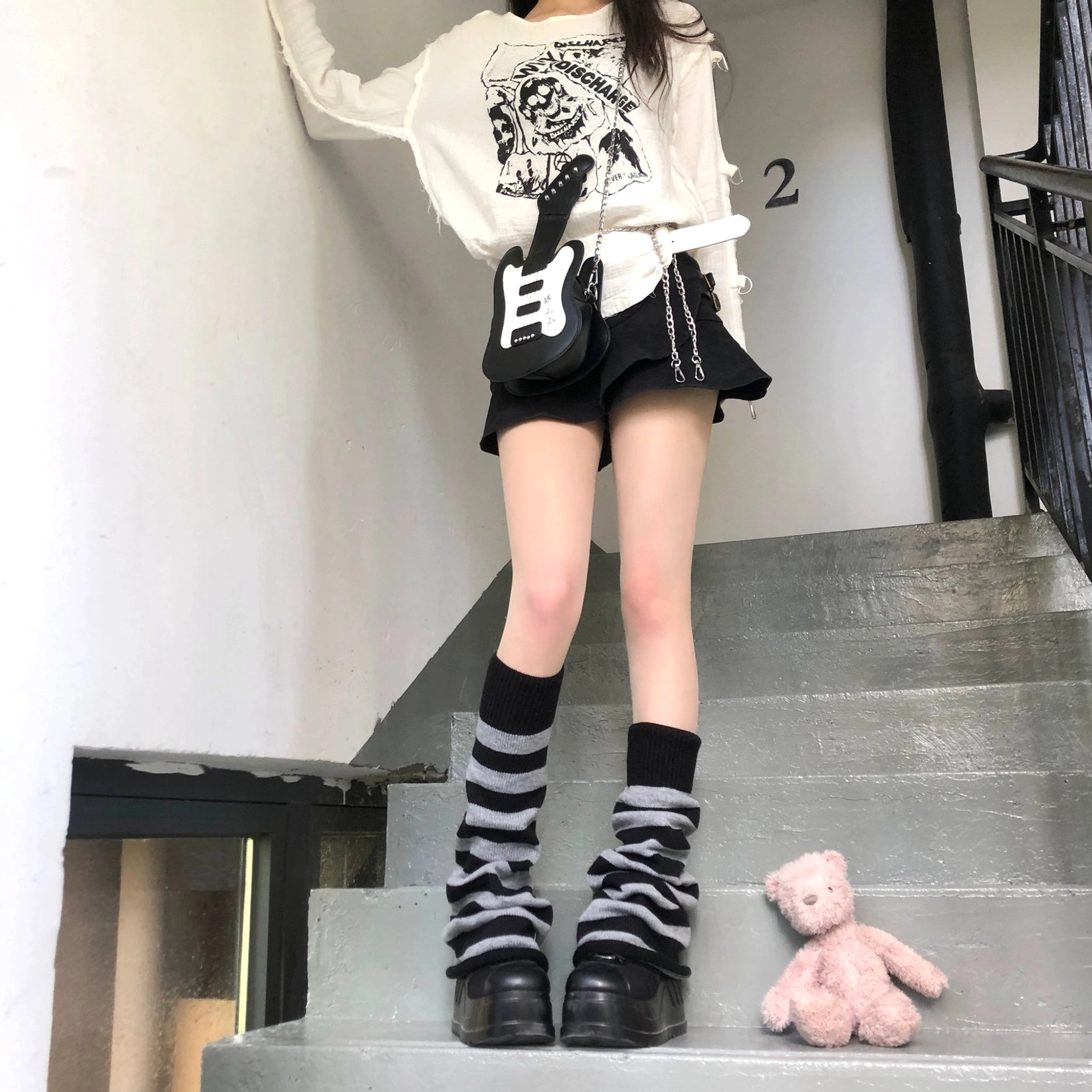 Grey and black horizontal stripe Y2K leg warmers slouchy cuffs front full view model wearing ripped top and shorts on staircase