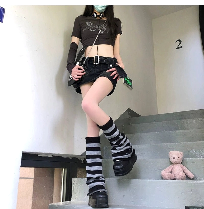 Grey and black horizontal striped Y2K leg warmers slouchy style front full view worn with mini skirt and cropped top on staircase