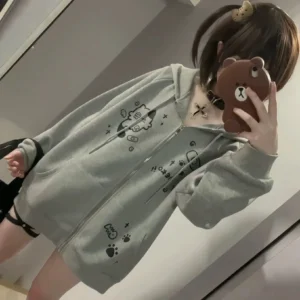 Grey oversized cat ear zip hoodie worn by model in mirror selfie showing loose fit cute cartoon prints cross necklace and choker styling