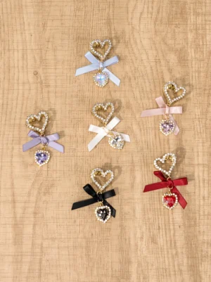 Overhead view of heart rhinestone hair clips collection featuring all six color variations mixed styles with varied bow and gem tones arranged on rustic wooden board surface