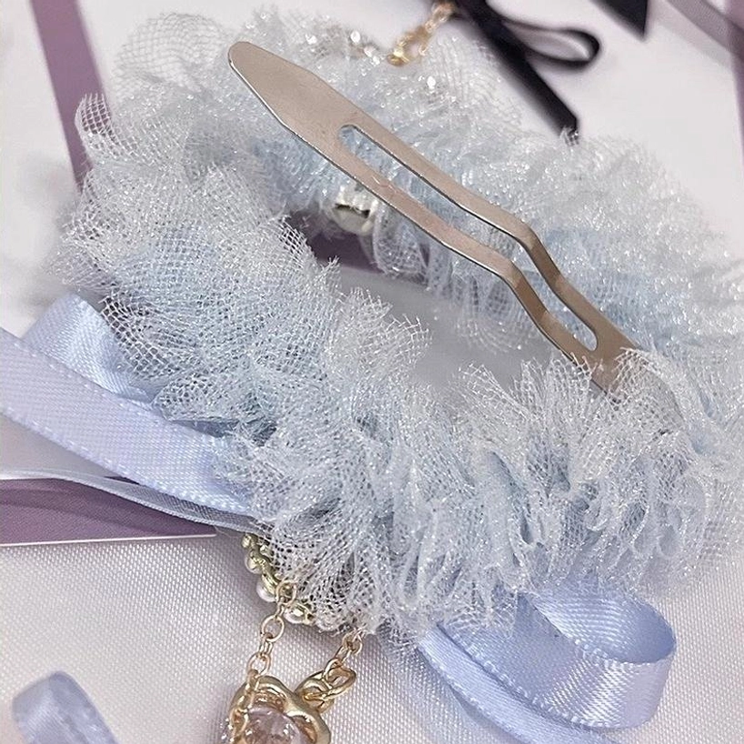 Close-up side profile view of light blue heart-shaped tulle hair clip showing metal fastener mechanism and hanging heart charm