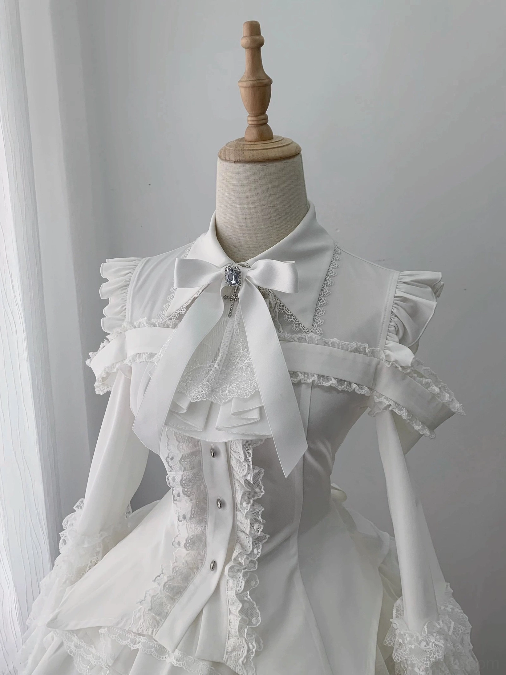 Close-up front detail of hime sleeve blouse with bow necktie brooch lace front trim and button-up front closure