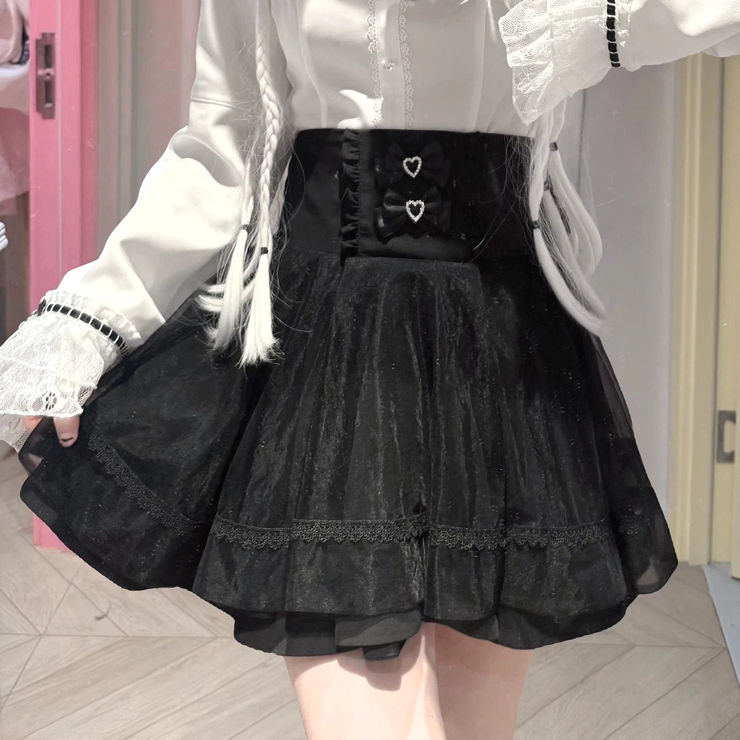 Lower body close-up of jirai kei high-waisted a-line skirt with double heart-shaped rhinestone buckles, layered tulle construction, and lace trim details