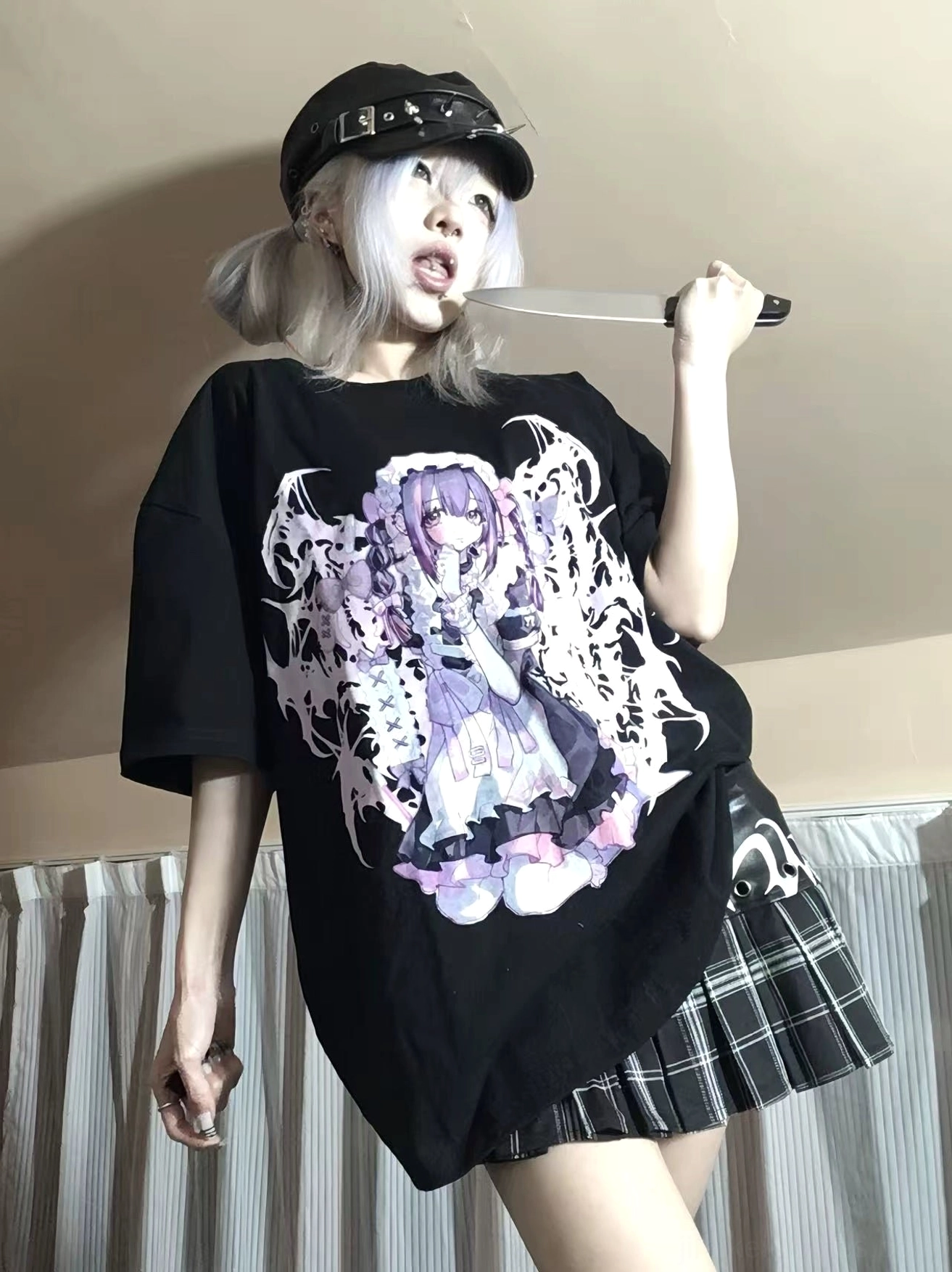 Side view half-body shot of black oversized Jirai Kei anime graphic t-shirt styled with plaid mini skirt on model with silver twin buns, demonstrating Y2K gothic fashion coordination