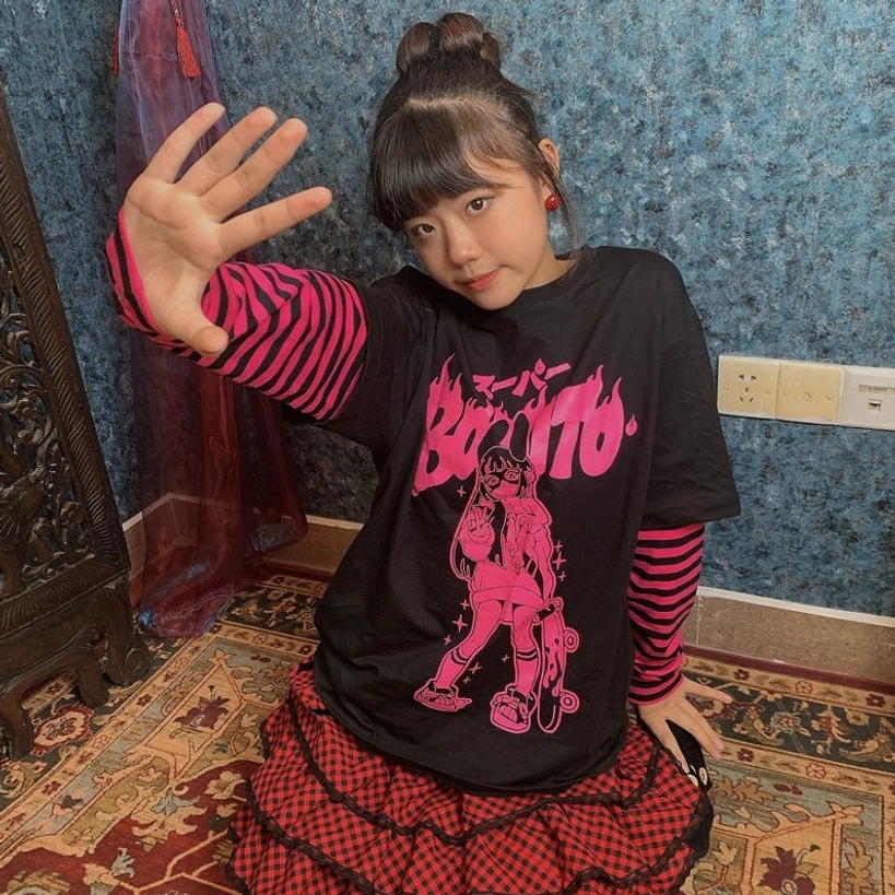 Side-front half-body shot of black-base jirai kei fake two-piece tee with red-pink striped sleeves and pink flame-style text graphic print