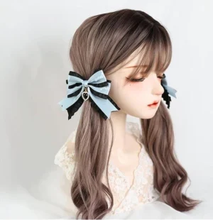 Jirai Kei black and blue dual-tone bow hair clips with rhinestone heart pendant and lace ruffle, displayed on brown twin-tail mannequin showing three-quarter view styling
