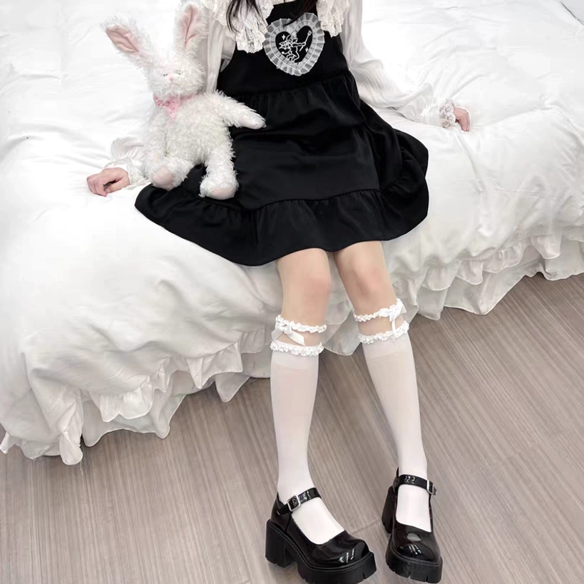 Close-up frontal view of black calf-length Jirai Kei lolita socks featuring ruffled mesh cuff with cross ornament and platform loafers