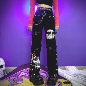 Female model wearing black Jirai Kei flared cargo pants with graffiti graphics, red cropped sleeve top, chain embellishments, and rivets - front full body shot showcasing dramatic pants silhouette
