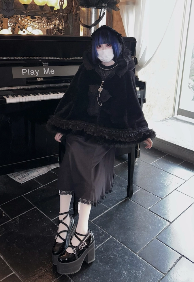 Front medium shot of black cat ear hooded fleece cape coat indoors, showing cape silhouette, white crew socks, platform Mary Jane shoes, plush fabric