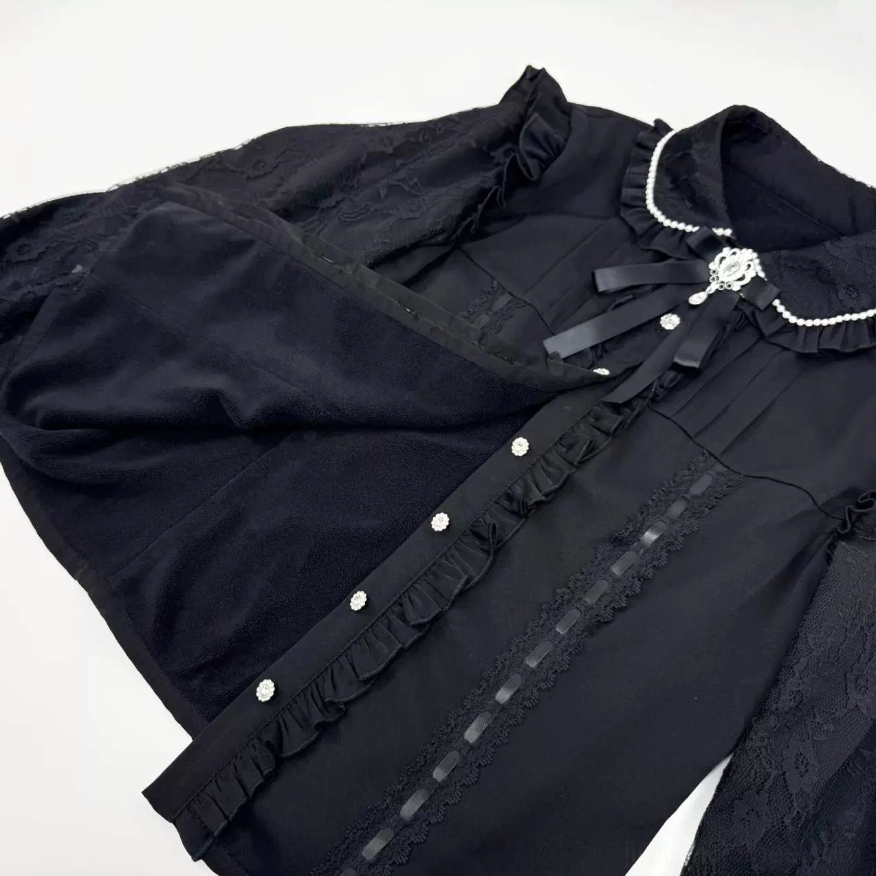 Close-up overhead view of black Jirai Kei fleece-lined blouse showing ruffled front trim and fleece lining detail