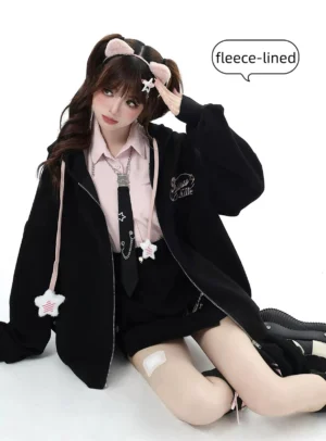 Black fleece-lined Jirai Kei hoodie jacket with pink inner wear and star drawstring, seated front view with butterfly camisole detail