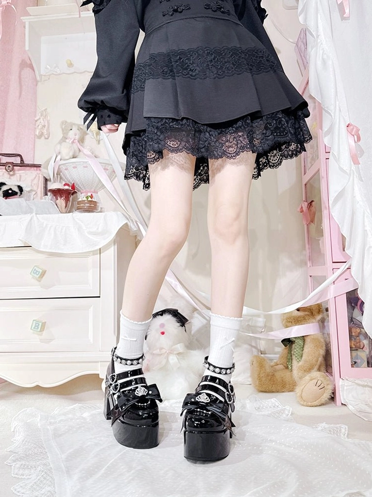 Black glossy Jirai Kei platform chunky heel shoes with rhinestone buckle decorations and thick block heel, worn with black lace-trimmed mini skirt