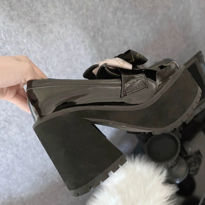 Jirai Kei black platform heels three-quarter view perspective showing glossy patent leather finish and curved architectural heel design