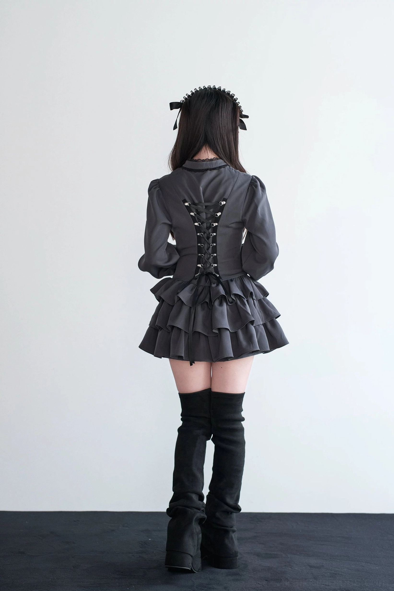 Back view of black Jirai Kei lace-up gothic dress showing intricate corset lacing and tiered ruffles