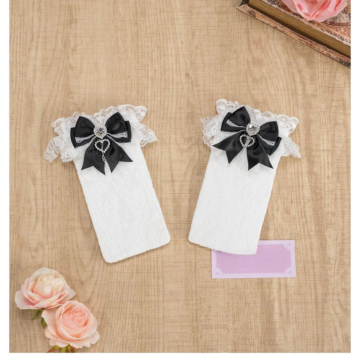 Classic black lace knee-high Jirai Kei socks with ruffled black lace cuff, black bow and heart rhinestone detail, full length front view