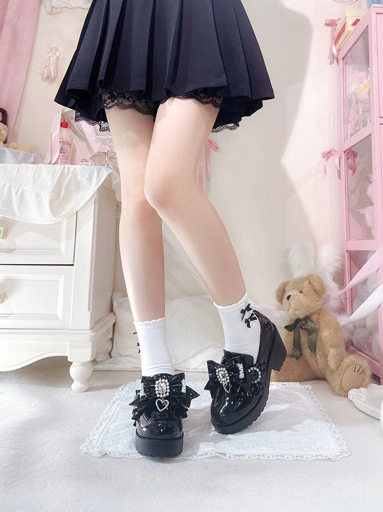 Front low angle dual-feet view of black patent leather Jirai Kei loafers with pleated JK skirt and white crew socks on pastel pink bedroom aesthetic for Japanese school style